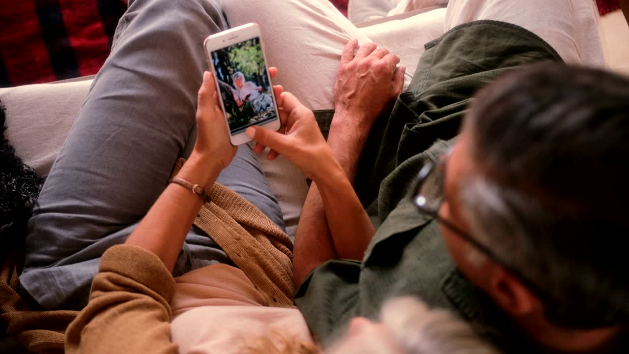 una pareja de ancianos en casa mirando fotografías en su teléfono inteligente
