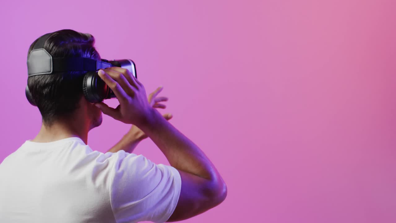 Video di uomo di origine mista che usa un visore VR su sfondo rosa e viola