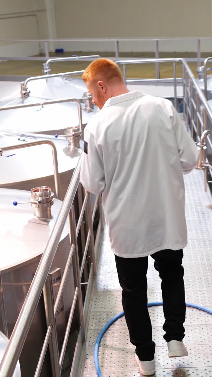 Man in Industrial Setting with Stainless Steel Tanks