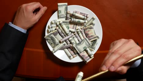 hands of a businessman with chopsticks and dollar rolls. eating dollars. 4k.