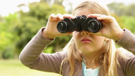 una niña linda usando binoculares en el parque