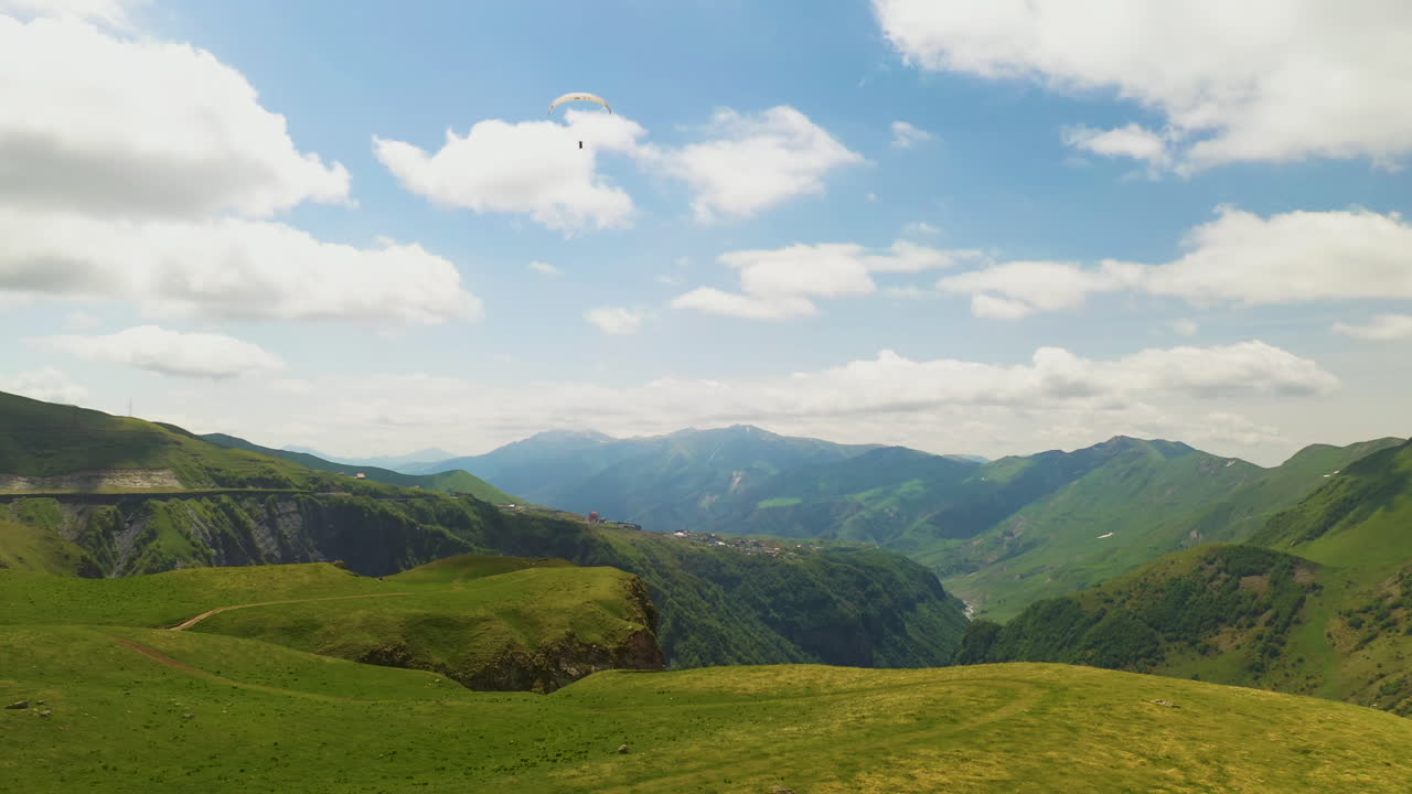 amplia toma cinematográfica de parapente volando en las montañas del cáucaso en gudauri georgia girando y revelando el valle