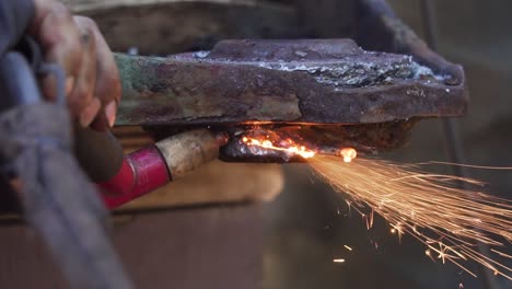 man´s hand holding a blowtorch tool welding metal - slowmotion