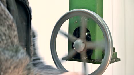 close-up of hands a male researcher rotates the manual wheel of the opening mechanism of the dome leaves of a solar observatory. scientific research observation station