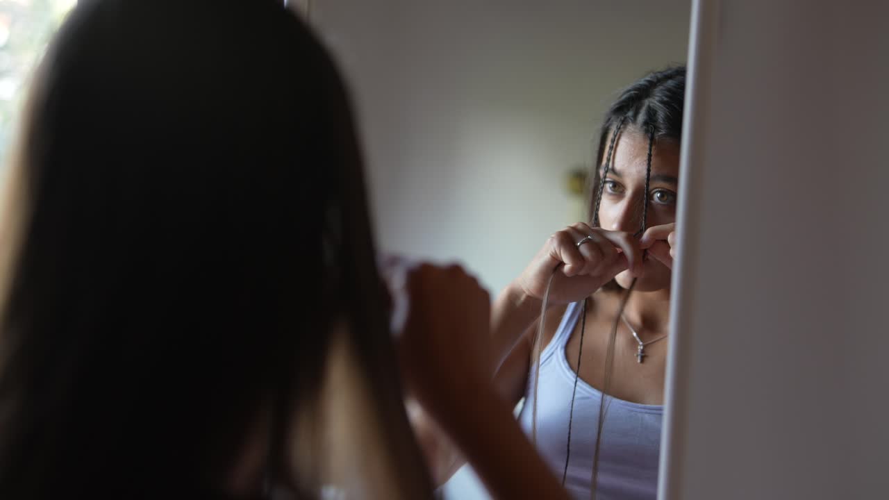 Donna che si intreccia i capelli davanti a uno specchio