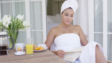 mujer en toalla de baño leyendo un libro en la mesa