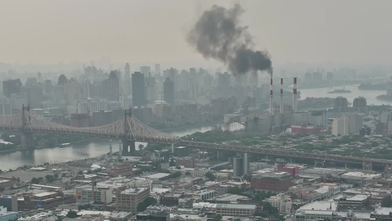 Drone view of industrial New York skyline with smoke rising above river