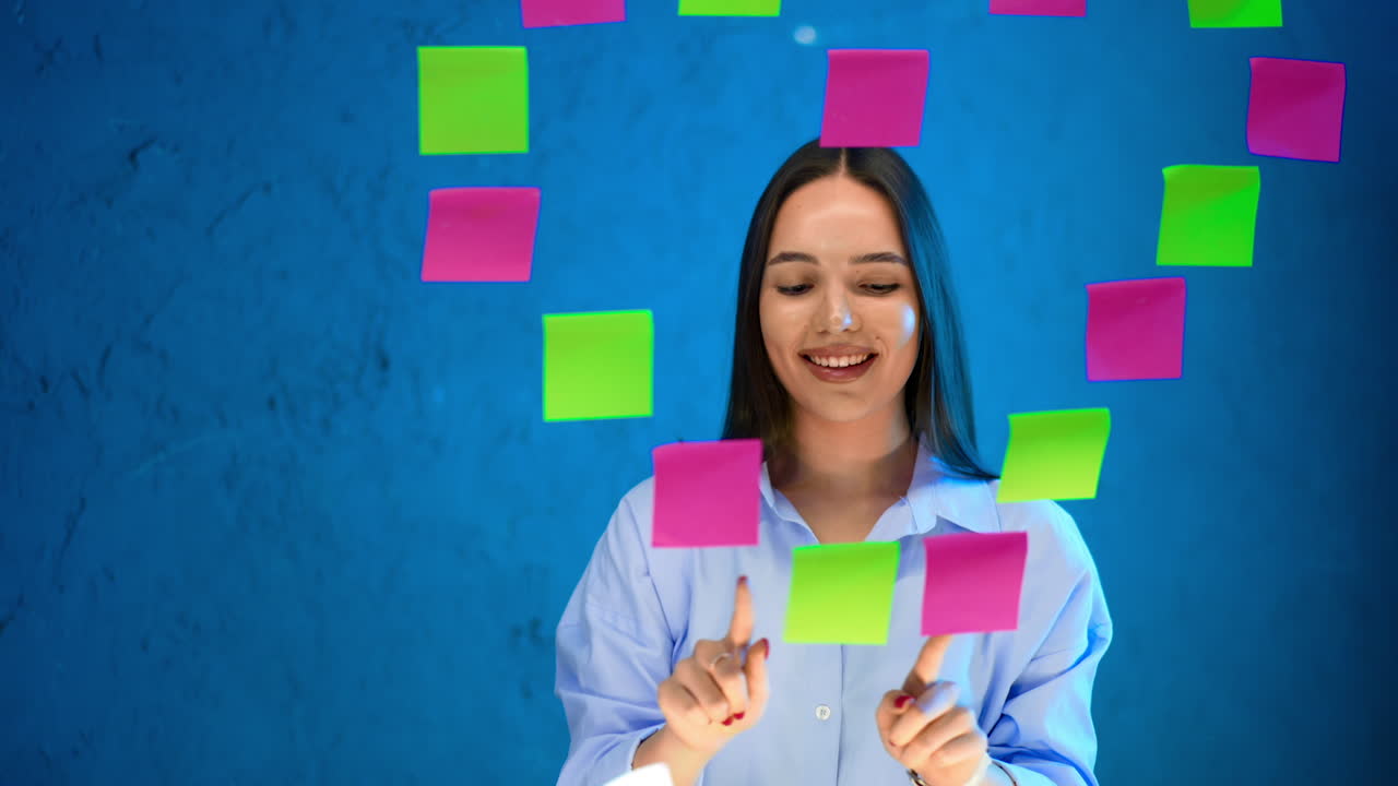 Sticky note brainstorming. A young woman smiles as she arranges colorful sticky notes on a blue wall, engaging in a brainstorming activity