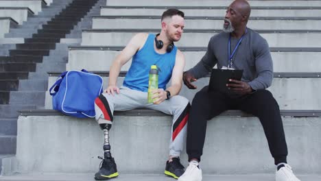 Diverser-Männlicher-Trainer-Und-Behinderter-Sportler-Mit-Beinprothese-Reden-Während-Der-Trainingseinheit
