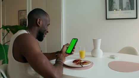 hombre comiendo panqueques y usando el teléfono