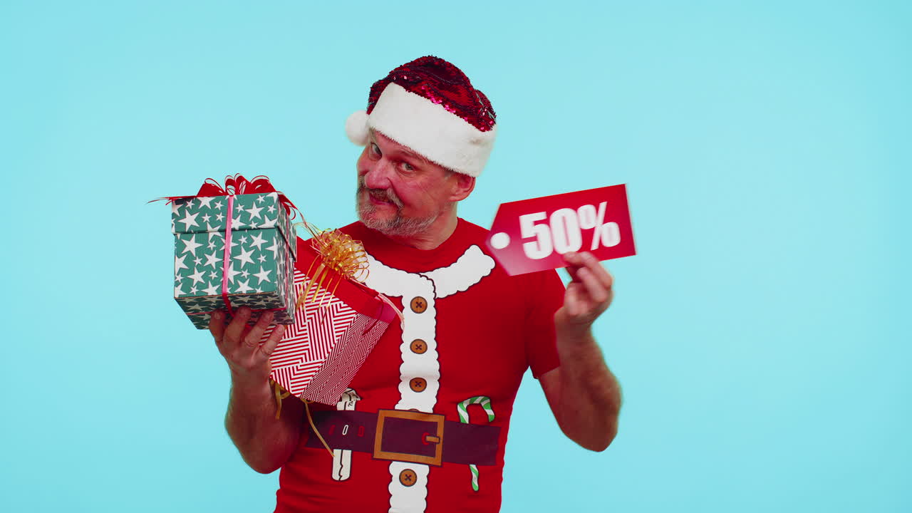 hombre con camiseta roja de navidad mostrando caja de regalos y inscripciones de descuento del 50 por ciento nota de texto de banner