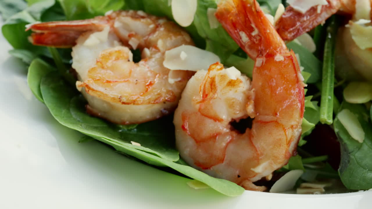Primo piano di gamberetti serviti su un'insalata verde fresca con condimenti