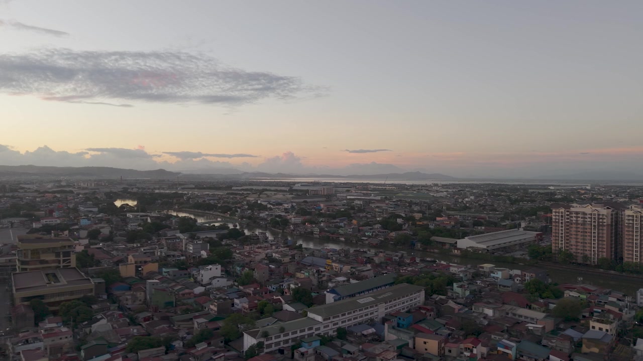 Filmato di drone che si sposta a sinistra sopra Metro Manila durante il crepuscolo con quartieri urbani densi, viste dello skyline e luce del tramonto che svanisce