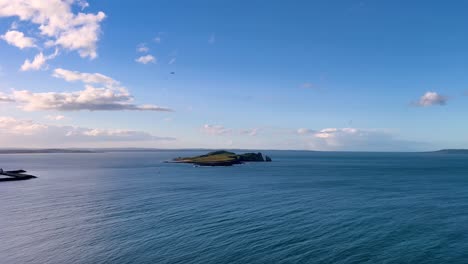 Ireland's-Eye:-Sunny-Day-Seascape-with-Beautiful-Blue-Sea,-Clouds,-Waves,-and-Plane-Landing-in-the-Distance