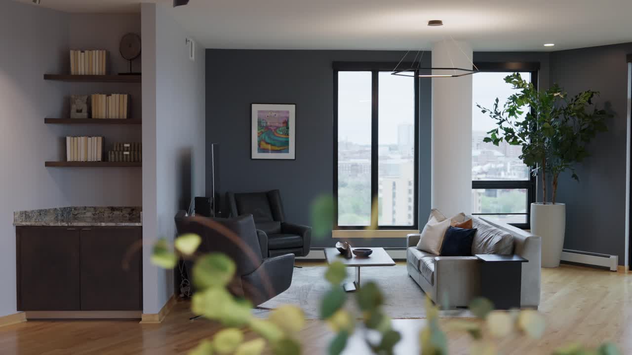 Orbiting shot of a modern living room with large windows, stylish furniture, built-in shelves, and wood flooring