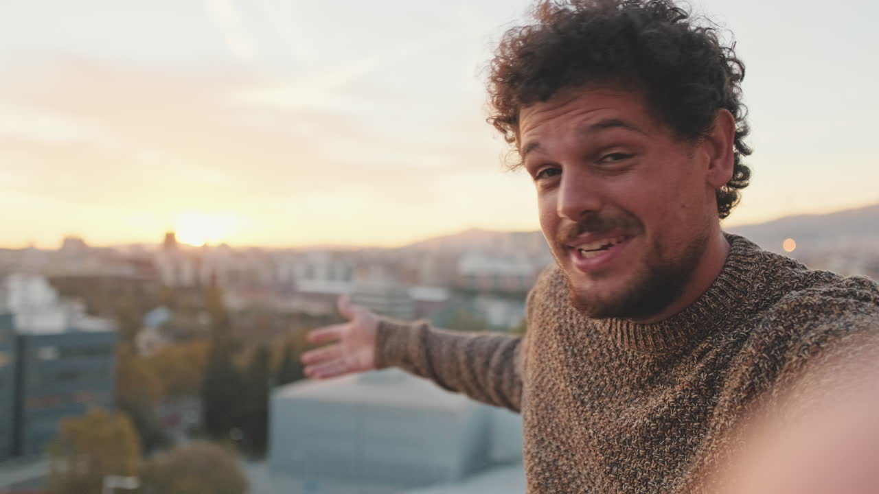 Man taking a selfie on a rooftop at sunset
