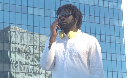 stylish black man speaking on smartphone on urban pavement