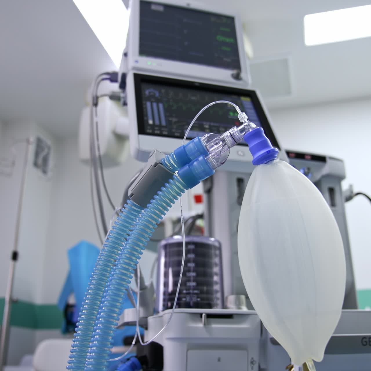 Contemporary lung ventilation system working in modern surgical room. Ambu bag inflating at foreground