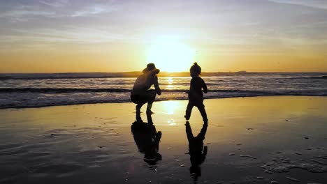 a child runs to mom's arms in 4k during a stunning sunset at the beach with a colorful sky
