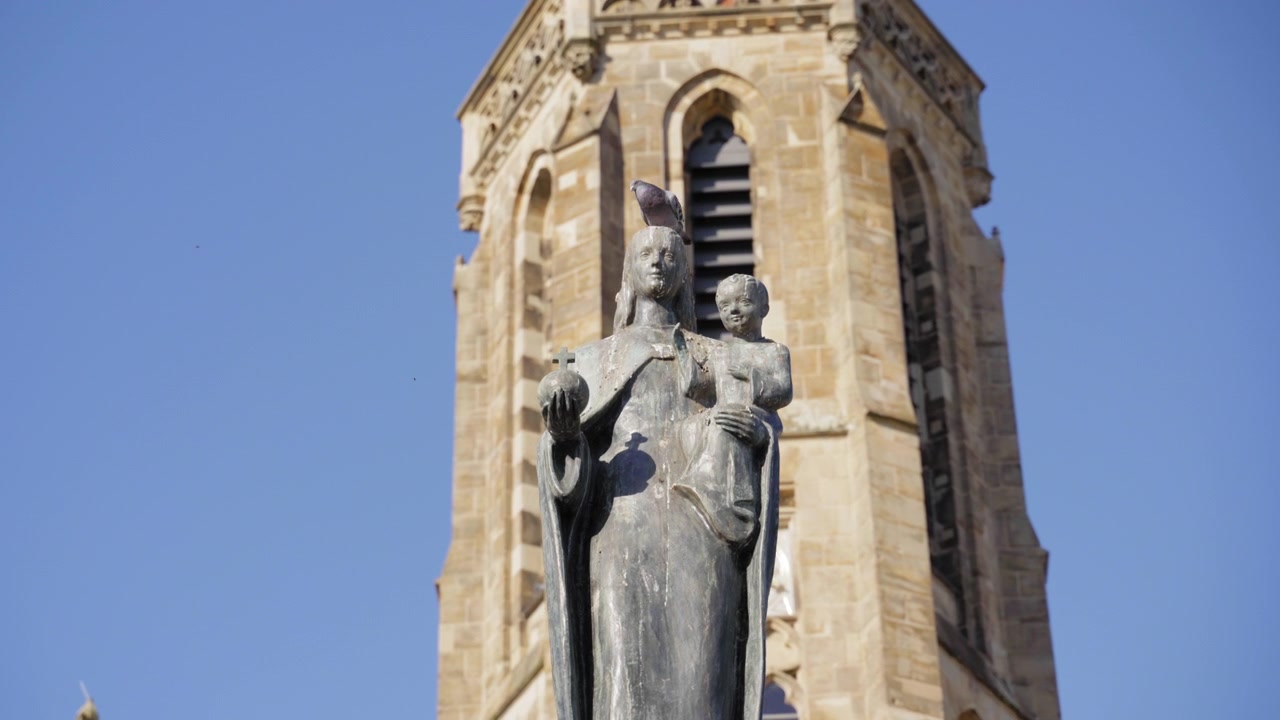 Vista ravvicinata della statua della Vergine Maria con il Bambino e della storica torre della Chiesa di San Ludovico a Saarlouis, Germania