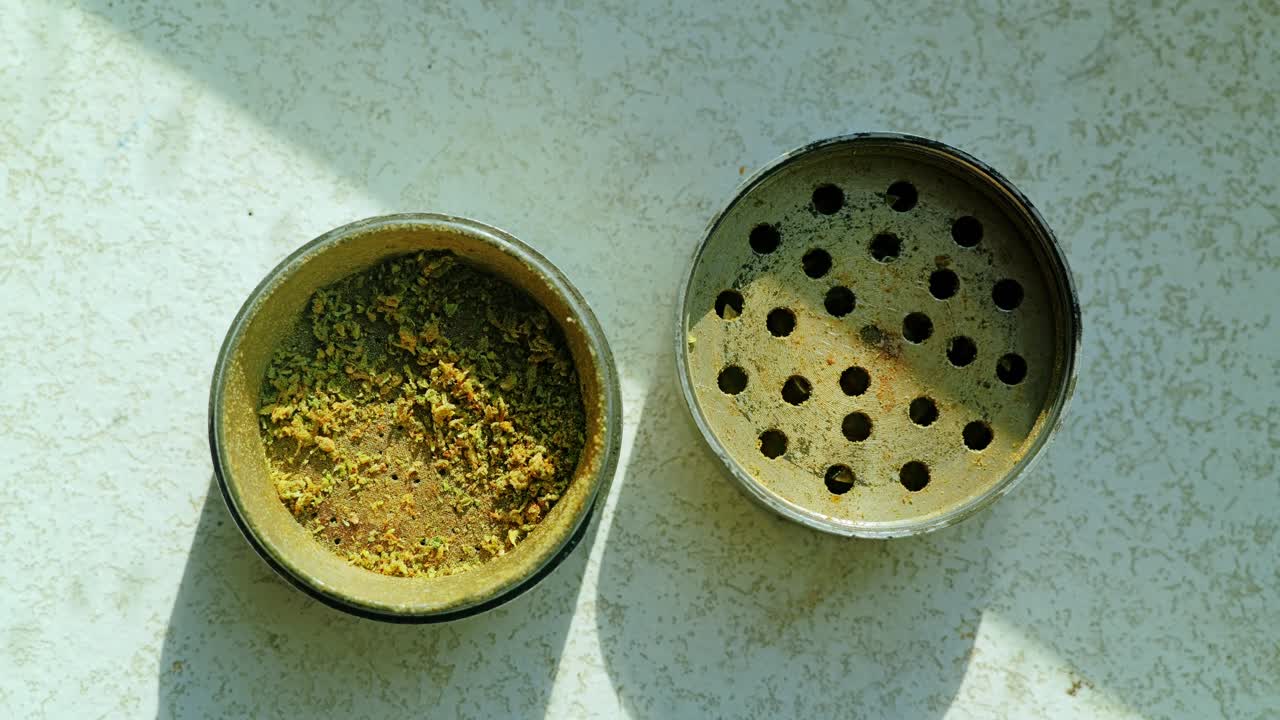 Closeup view of metal grinder containing crushed herbs symbolizing cooking use