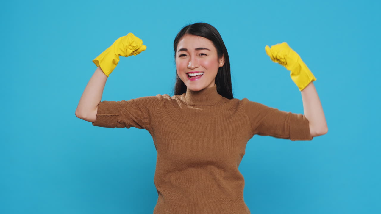 Overjoyed housekeeper wearing protective gloves while doing win gesture in front of camera