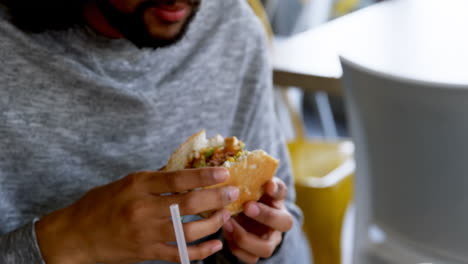 hombre comiendo una hamburguesa en un café 4k