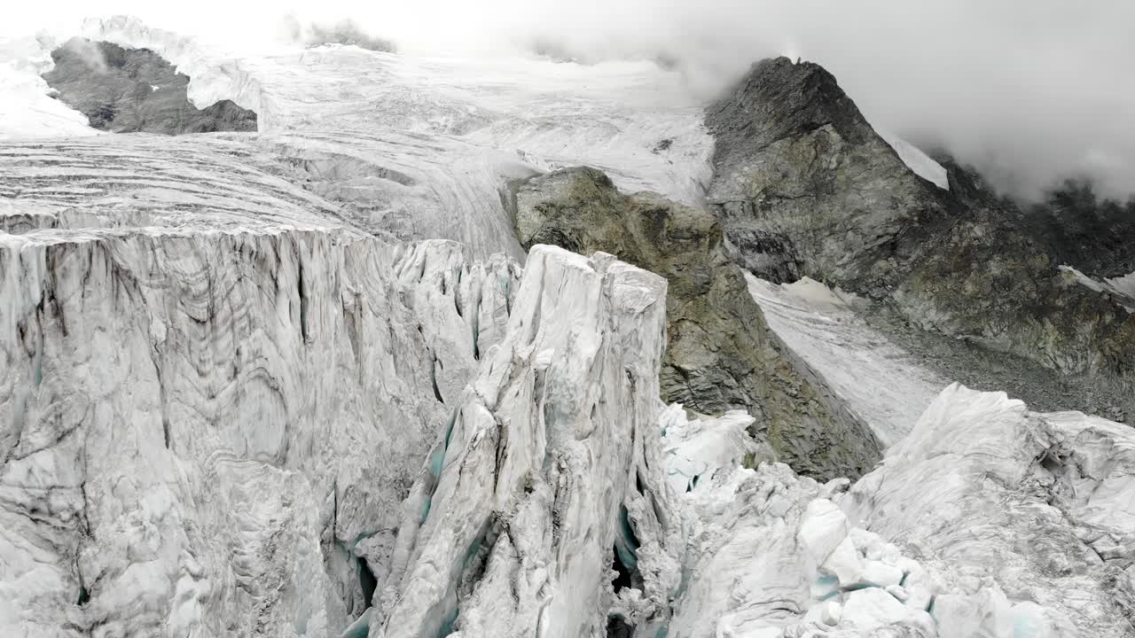 Aerial flyover through the ice crevasses of the Moiry glacier near Grimentz in Valais, Switzerland with on a cloudy summer afternoon