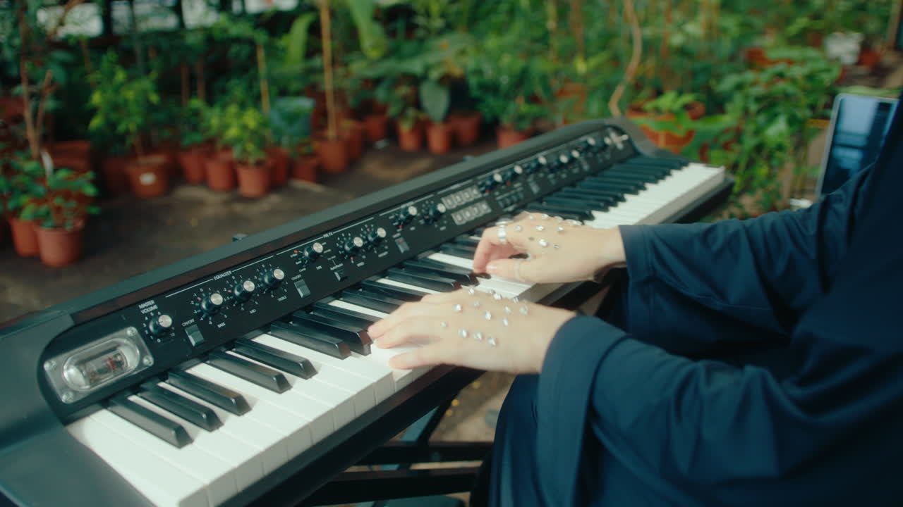 Gem-Adorned Hands of Female Pianist Playing Keyboard in Lush Greenhouse