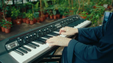 gem-adorned hands of female pianist playing keyboard in lush greenhouse