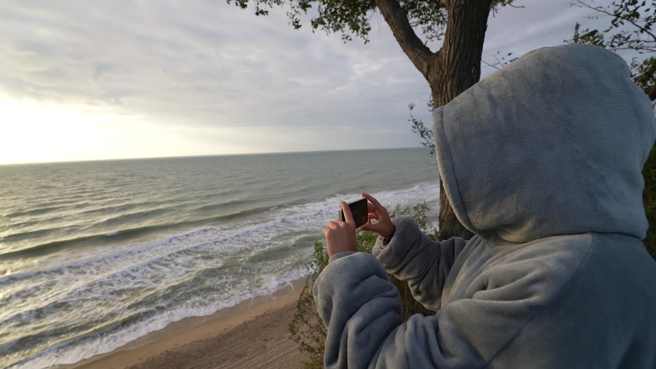 바다 해변 위에서 해가 뜨는 사진을 찍는 사람