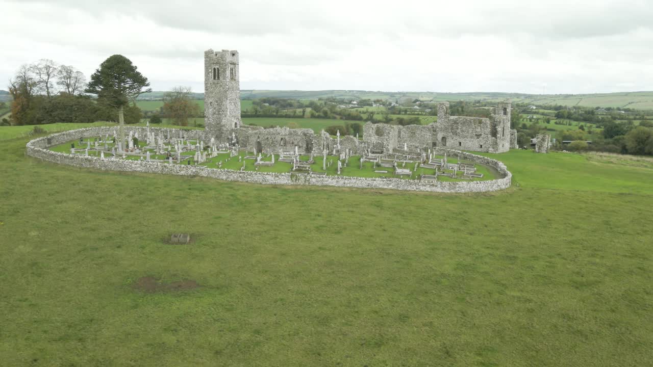 Hill of Slane monastery ruins with ancient tower and cemetery in lush green Irish countryside