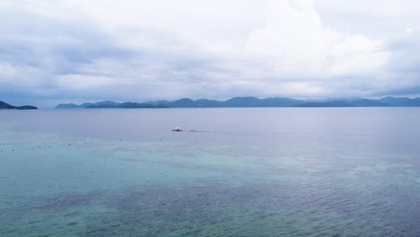 Drone-Aéreo-Elevándose-Sobre-Un-Pequeño-Barco-Pesquero-En-El-Popular-Lugar-De-Buceo-En-Naufragios-De-La-Segunda-Guerra-Mundial-En-La-Bahía-De-Coron-En-Palawan,-Filipinas