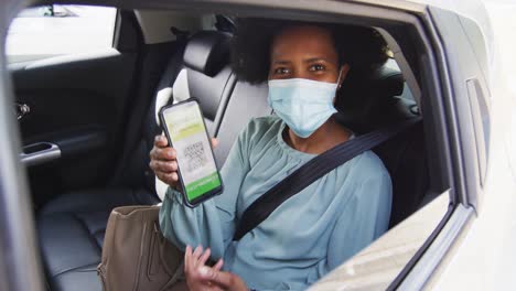 Portrait-of-african-american-businesswoman-with-face-mask-with-covid-19-certification-on-smartphone