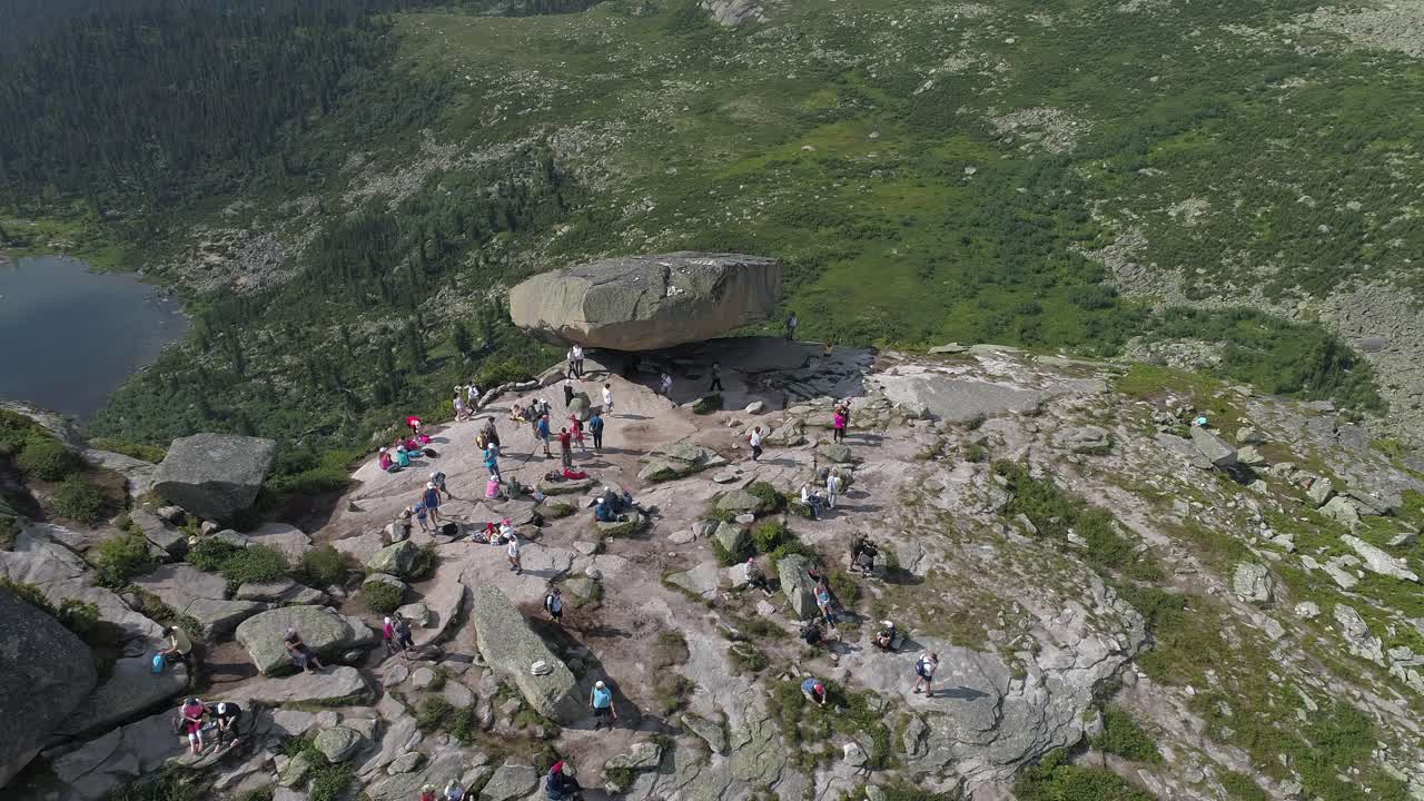 vista aérea de una gran formación rocosa con personas caminando en las montañas