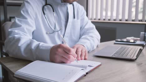 concentrated professional young doctor in glasses and uniform is working in his office doing paperwork. writing a diagnosis, treatment plan. a doctor at his workplace. vertical video