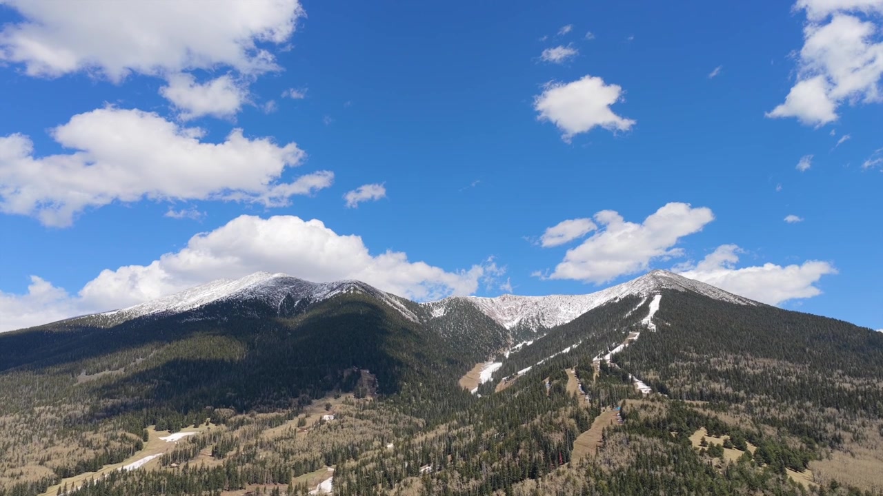 Un video drone 4K cattura l'intersezione tra foresta alpina e attività ricreative invernali. Il movimento rivela sentieri innevati sul Monte Humphreys con sciatori che si muovono attraverso un aspro paesaggio dell'Arizona.
