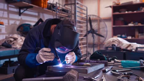 welder using tig welding machine to connect steel frame inside workshop