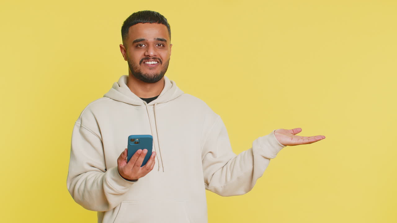 Man using smartphone showing pointing empty place advertising application area positive feedback