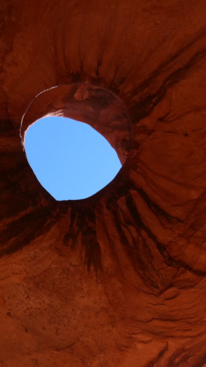 Woman Walking in Desert and Looking Up at Natural Rock Arch