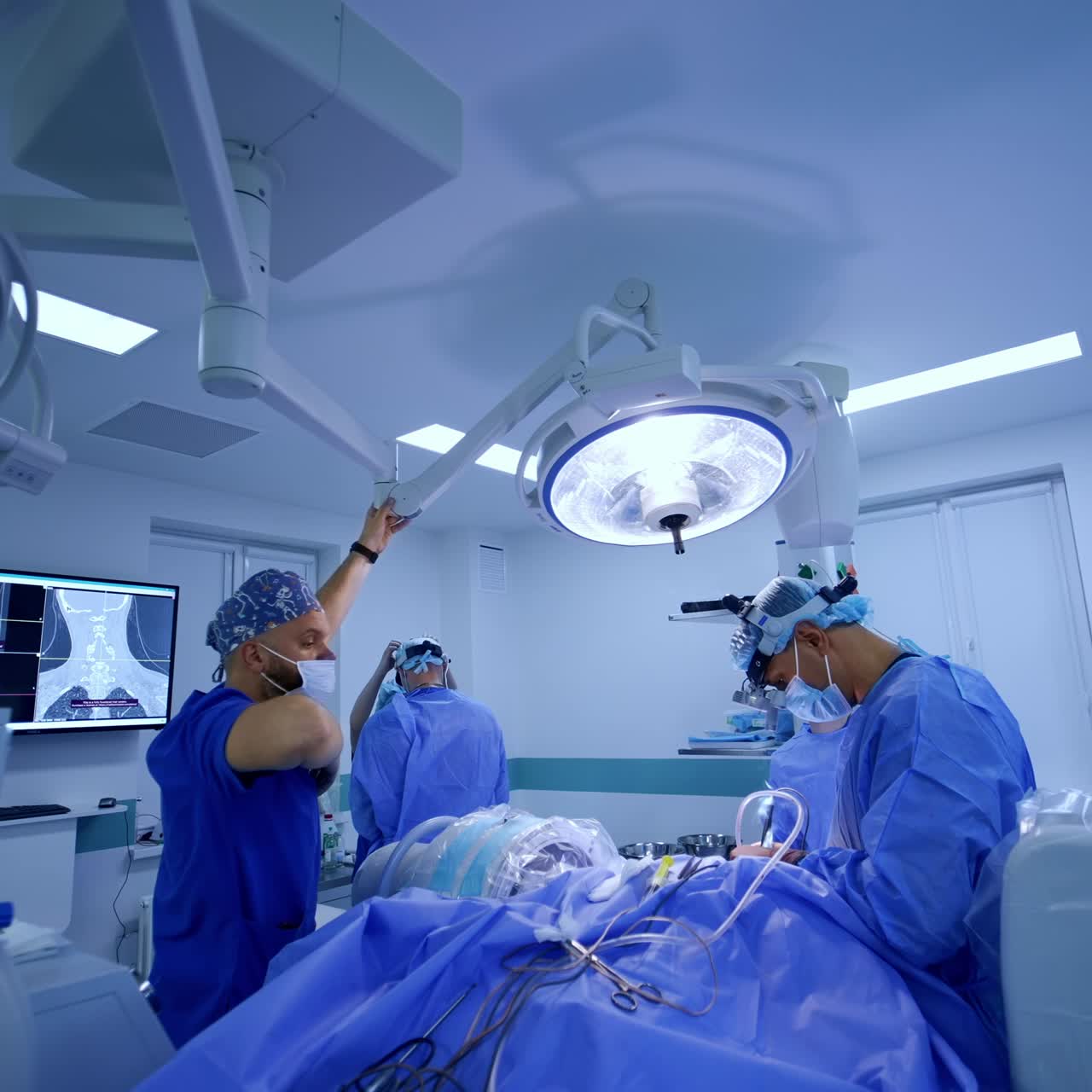 Anesthesiologist fixing the illumination in surgery room during operation. Neurosurgeon uses electric tool performing procedure