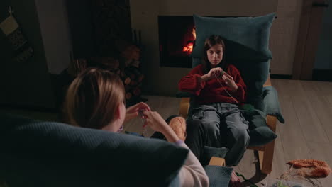 mother and daughter knitting by the fireplace