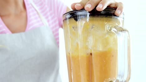 Mid-section-of-woman-preparing-smoothie