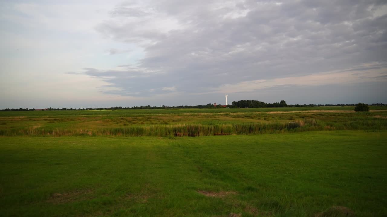 campo en el norte de alemania con buen tiempo con una turbina eólica en el horizonte