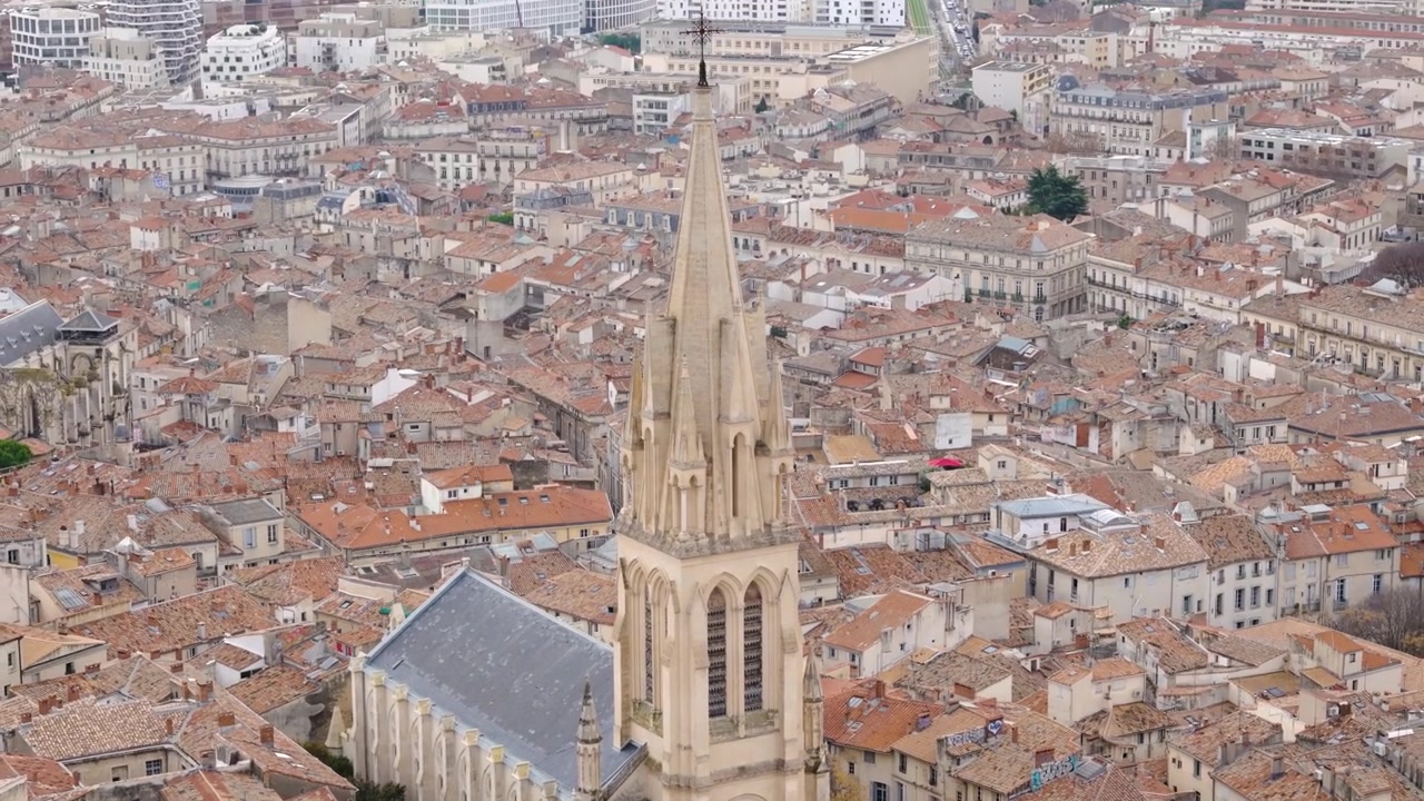Il drone si allontana e si inclina verso l'alto da una chiesa gotica sui tetti di Montpellier