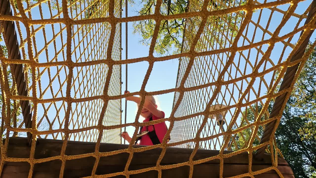 счастливая маленькая девочка играет в аттракционе тарзана на игровой площадке в парке развлечений