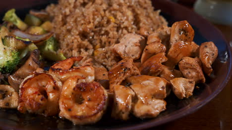 Mixed-meat-hibachi-plate,-shrimp-vegetable-chicken-fried-rice-piled-on-plate,-slider-close-up-4K