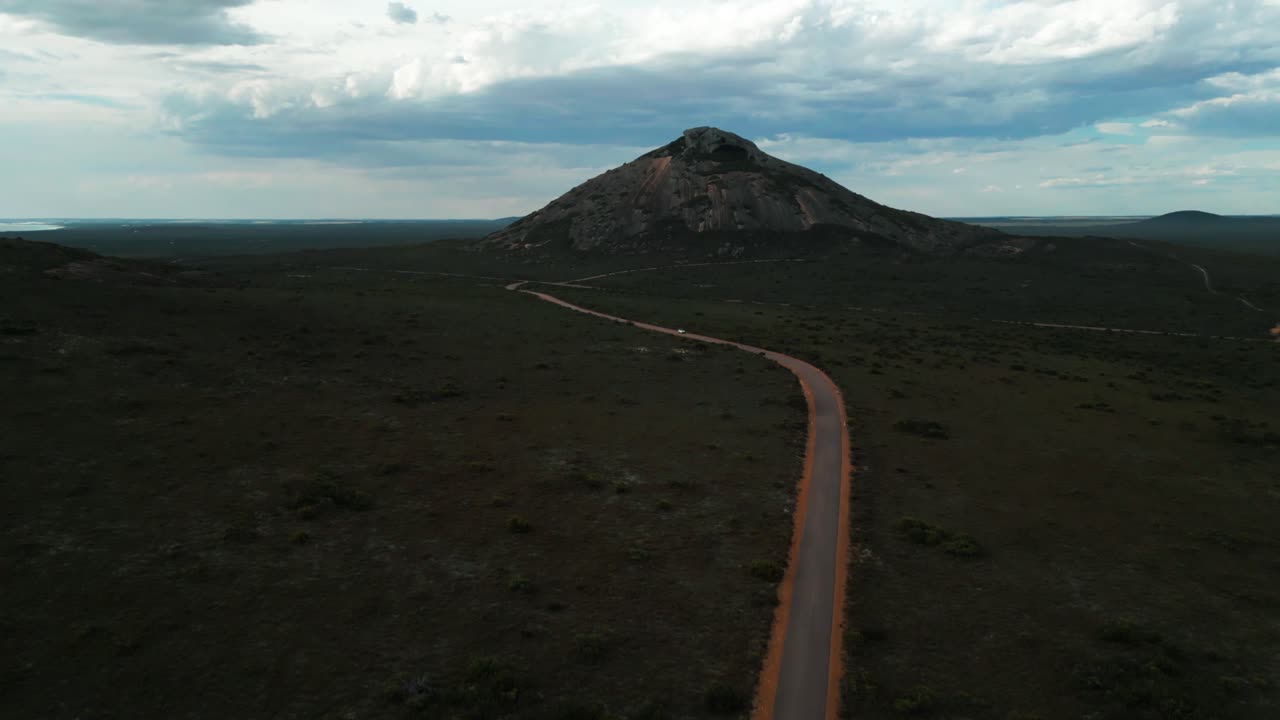 aerial shot over hellfire road in Cape Legrand National Park with a van driving on a dirt road to hellfire bay with the frenchman peak in the background on a cloudy day in Western Australia