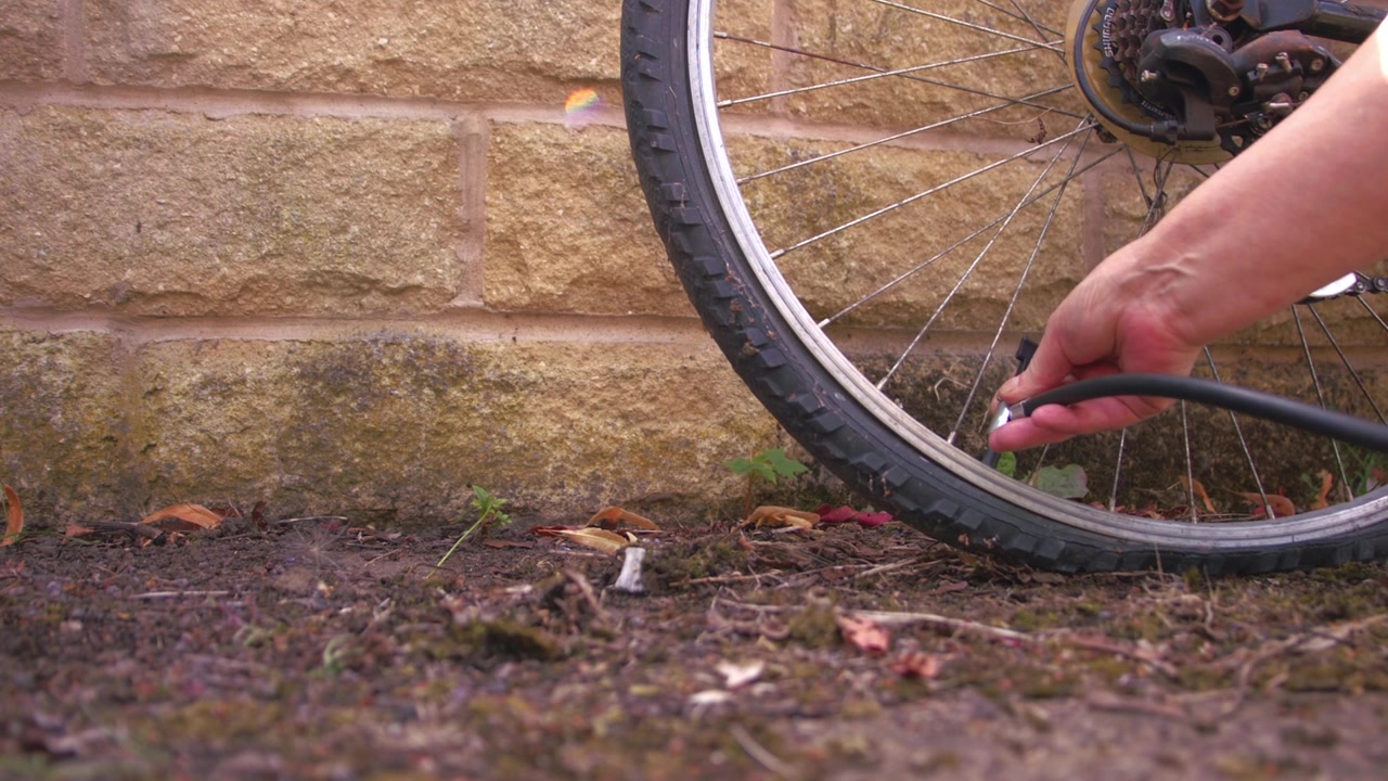 Cyclist pumping flat tyre on bicycle close up zoom slow motion shot selective focus