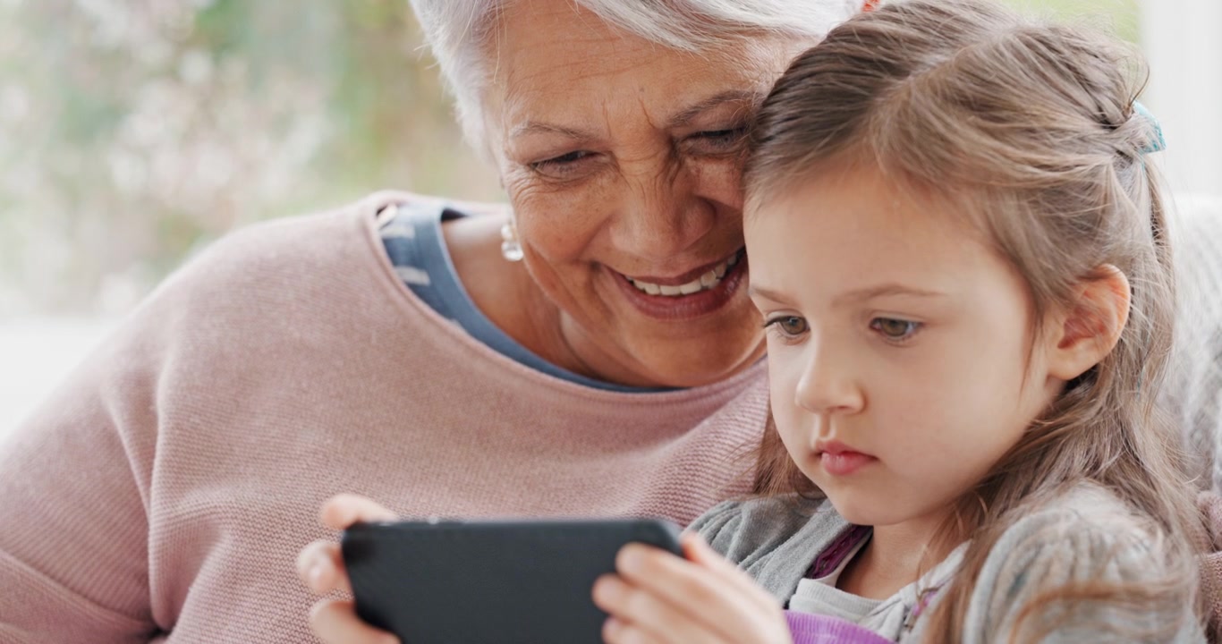 Bedstemor og barnebarn bruger en tablet sammen derhjemme